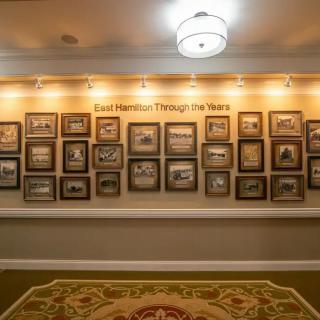 A hallway featuring a wall display of framed historic photos illuminated by overhead lights.