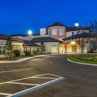 A well-lit building with a parking lot at night.