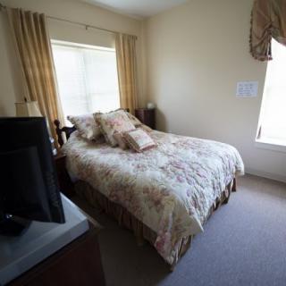 A cozy bedroom with a neatly made bed, pillows, and a television.