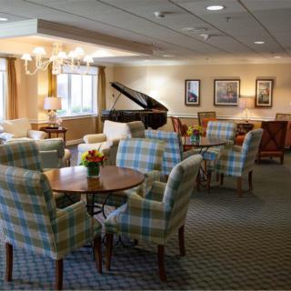 A cozy lounge area featuring a grand piano, comfortable seating, and warm lighting.