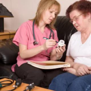 A nurse discusses medication with a patient during a home visit.