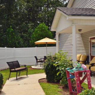 A cozy outdoor patio with a seating area and play space, surrounded by greenery.