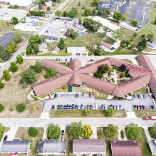 An aerial view of a uniquely designed building surrounded by greenery and a parking lot.