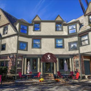 A charming restaurant with outdoor seating, surrounded by picturesque architecture and a clear blue sky.