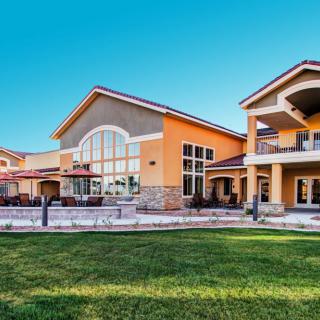 A spacious residential building with a neatly manicured lawn under a clear blue sky.