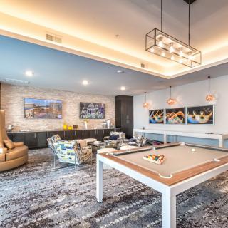 A modern game room featuring a stylish pool table, comfortable seating, and contemporary artwork.