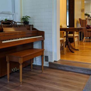 A cozy living space featuring a wooden piano and a view into the dining area.