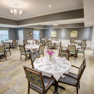 An elegant dining room with neatly arranged tables and chairs, set for a formal dining experience.