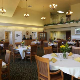 A well-appointed dining room with neatly arranged tables and chairs, featuring elegant table settings and warm lighting.
