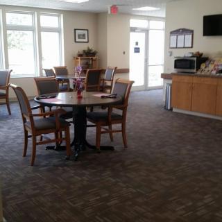 A well-lit dining area with tables and chairs, featuring a microwave and television.
