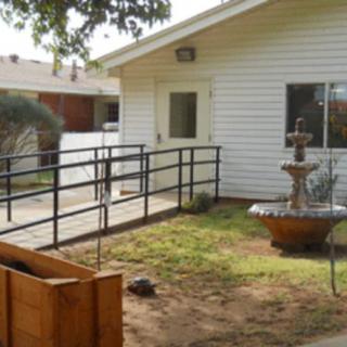 A house with a ramp leading to the entrance, featuring a yard and fountain.