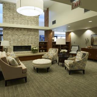A modern lobby with comfortable seating and a central fireplace.