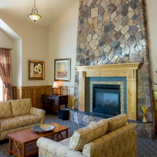 A cozy living room featuring a stone fireplace, comfortable couches, and warm wood paneling.