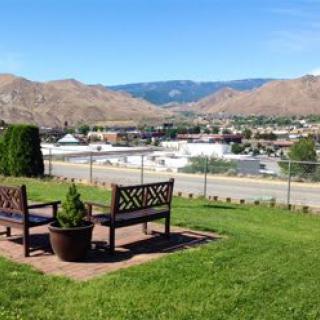 A scenic view of benches overlooking a city with mountains in the background.