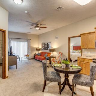 Open concept living space featuring a cozy sofa, dining table with chairs, and a kitchen area.