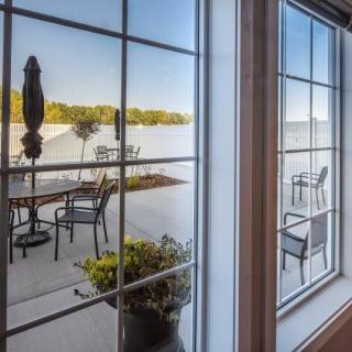 View of a lake and patio seating through a window.