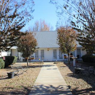 A front view of a house with a pathway leading up to it, surrounded by trees and landscaping.