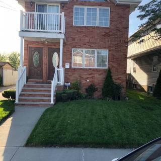A brick house with a small front yard and balcony.