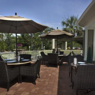 A cozy outdoor patio with seating and umbrellas on a sunny day.