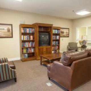 A cozy living room with a television, bookshelves, and comfortable seating.
