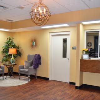A cozy and inviting waiting room featuring comfortable seating, decorative plants, and warm lighting.
