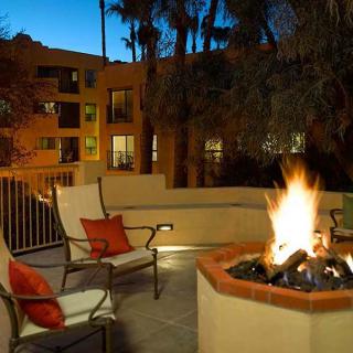 A cozy outdoor patio with a fire pit and seating area at an apartment complex during the evening.