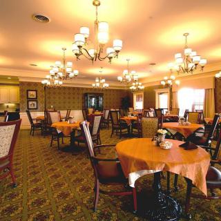 A warmly lit dining area with neatly arranged tables and elegant chandeliers.