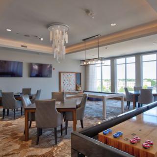 A modern game room with a foosball table, seating area, and large windows providing natural light.