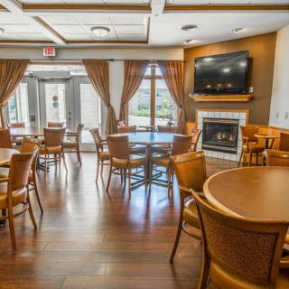 A cozy dining area featuring wooden tables and chairs, with a television and fireplace adding to the warm ambiance.