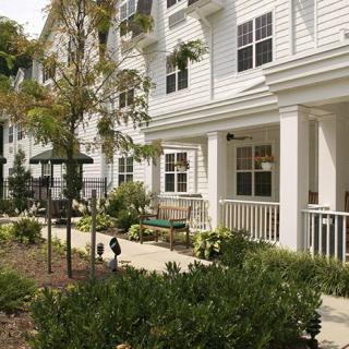 A well-maintained residential building with a landscaped garden and inviting porch area.