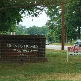 Entrance sign for Friends Homes at Guilford along a tree-lined road.