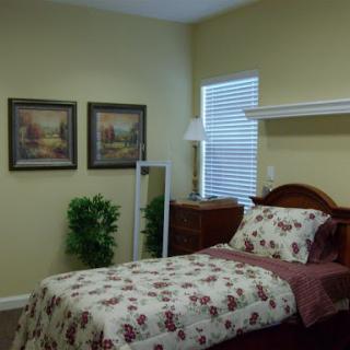 A cozy bedroom featuring floral bedding, decorative paintings, and warm wall colors.