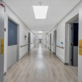 A clean and well-lit hospital corridor with multiple doors along the sides.