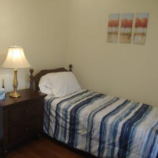 A cozy bedroom with a single bed, nightstand, and decorative wall art.