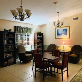 A cozy reading area with bookshelves, comfortable chairs, and a table under warm lighting.