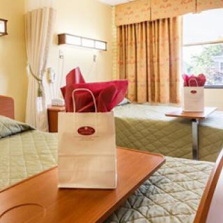 A cozy hotel room featuring two beds, a small table, and decorative elements.