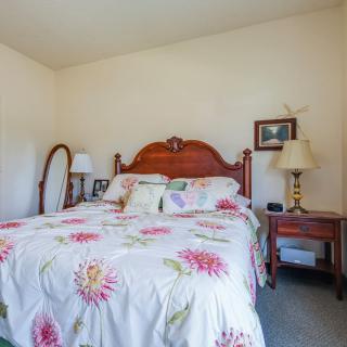 A cozy bedroom with floral bedding, a wooden headboard, and a bedside lamp.