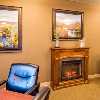 A cozy office interior with a decorative fireplace and framed artwork.