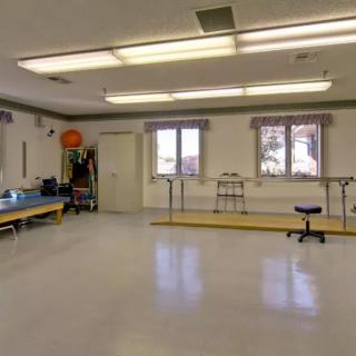 A rehabilitation therapy room equipped with exercise equipment and parallel bars.