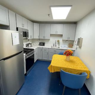 A modern kitchen featuring stainless steel appliances, a cozy yellow table setup, and blue flooring.