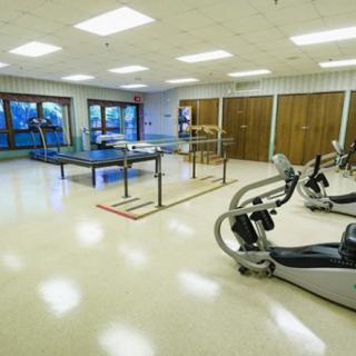 A spacious rehabilitation gym equipped with exercise machines and therapy tools.