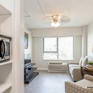 A modern apartment living room with a TV, chair, and a microwave.