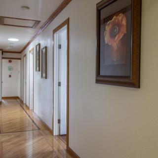 A well-lit hallway with framed artwork and wooden flooring.