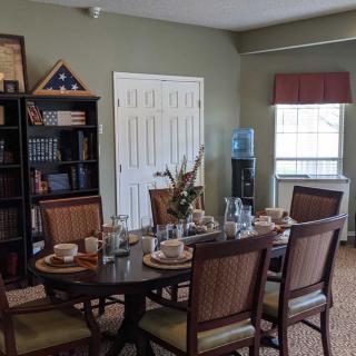A well-decorated dining room with a set table and bookshelf.