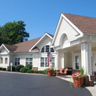 A well-maintained residential building with a front porch and an American flag displayed outside.
