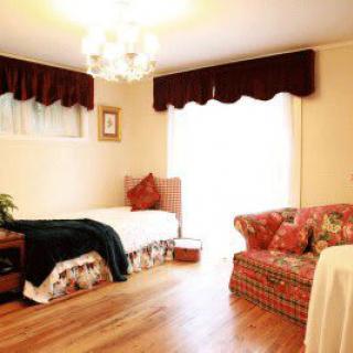 A cozy bedroom featuring a single bed and a patterned couch under a chandelier.