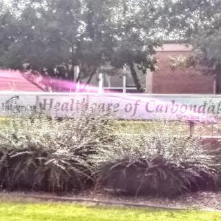 A sign for the Healthcare of Louisiana facility surrounded by greenery.