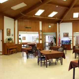 A spacious community dining room featuring wooden accents and tables set for gatherings.