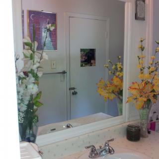 A bathroom with a mirror reflecting floral decorations and a closed door.