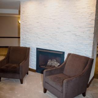 A modern living room with two brown chairs facing a stone fireplace.